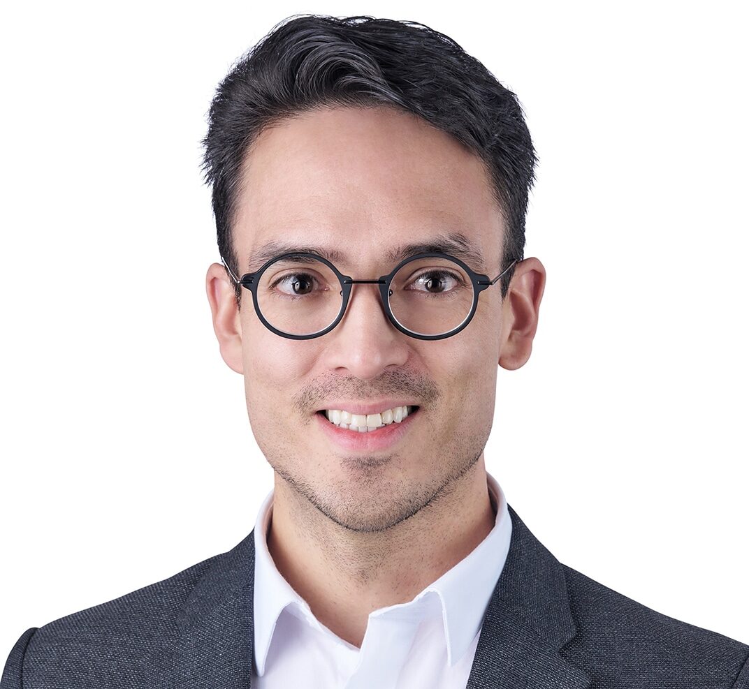 A headshot of associate Andres Bonnell. He has short black hair, and he is wearing black eyeglasses and a black blazer.