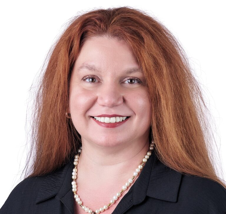 A headshot of associate Bethany Spencer Smith. She has long red hair and is wearing a black shirt.