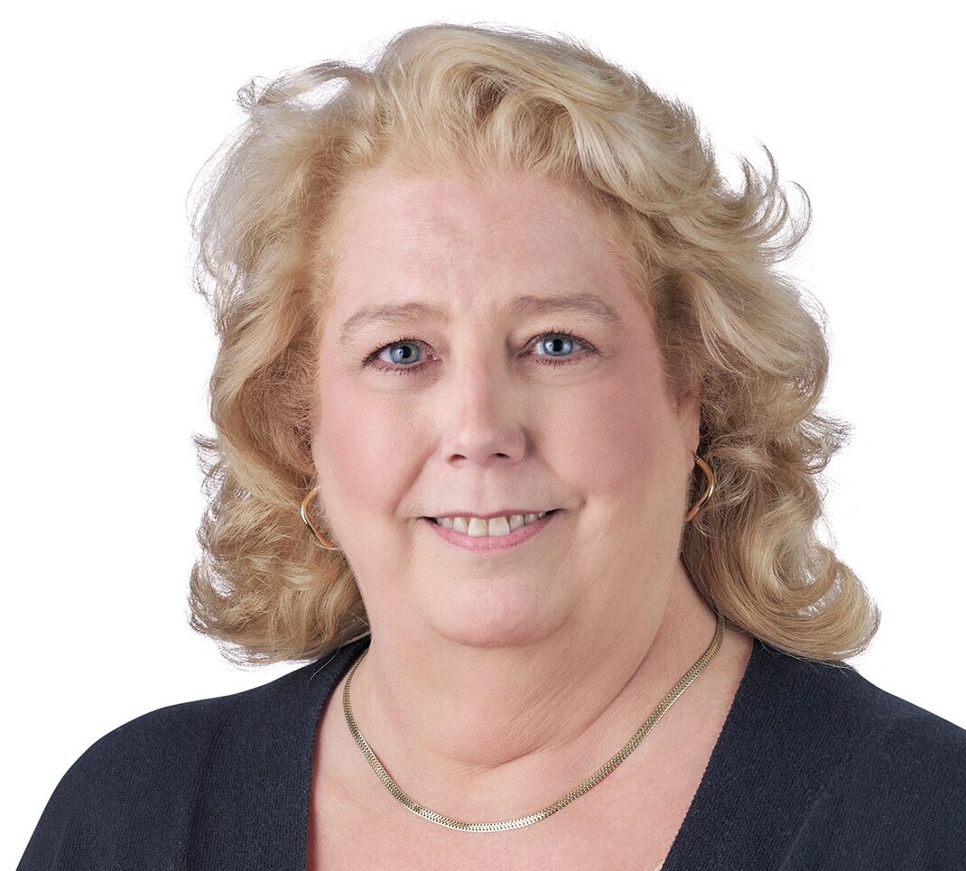 A headshot of associate Dana Haas. She has shoulder-length blonde hair, and she is wearing a black cardigan sweater.