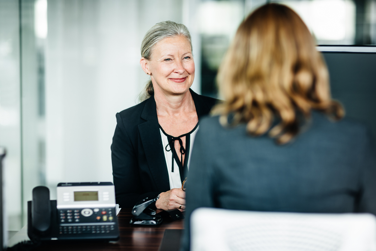 Two business partners sitting down and talking with each other at the office.
