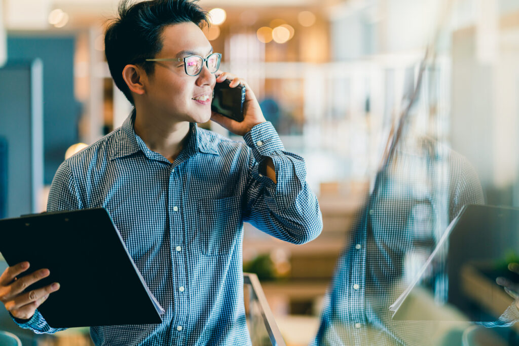A man holding a cell phone and a clipboard.