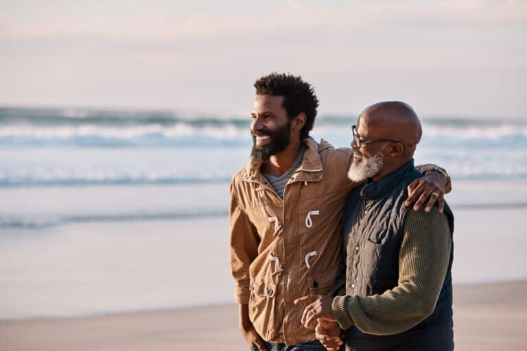 Father and son standing together on beach